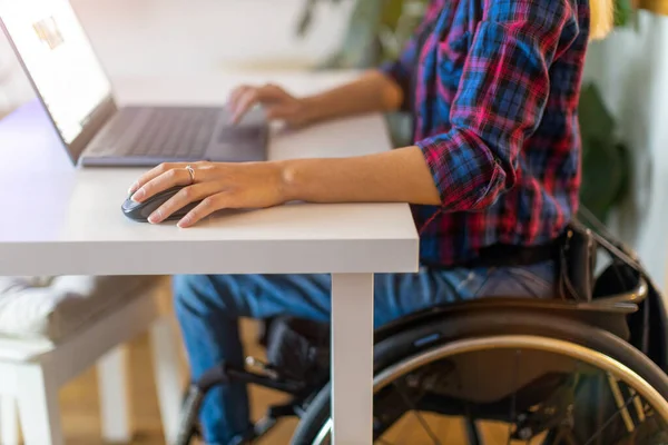 Woman in wheelchair using laptop in office