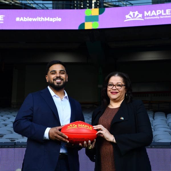 man and woman holding Maple branded football between them in sports stadium